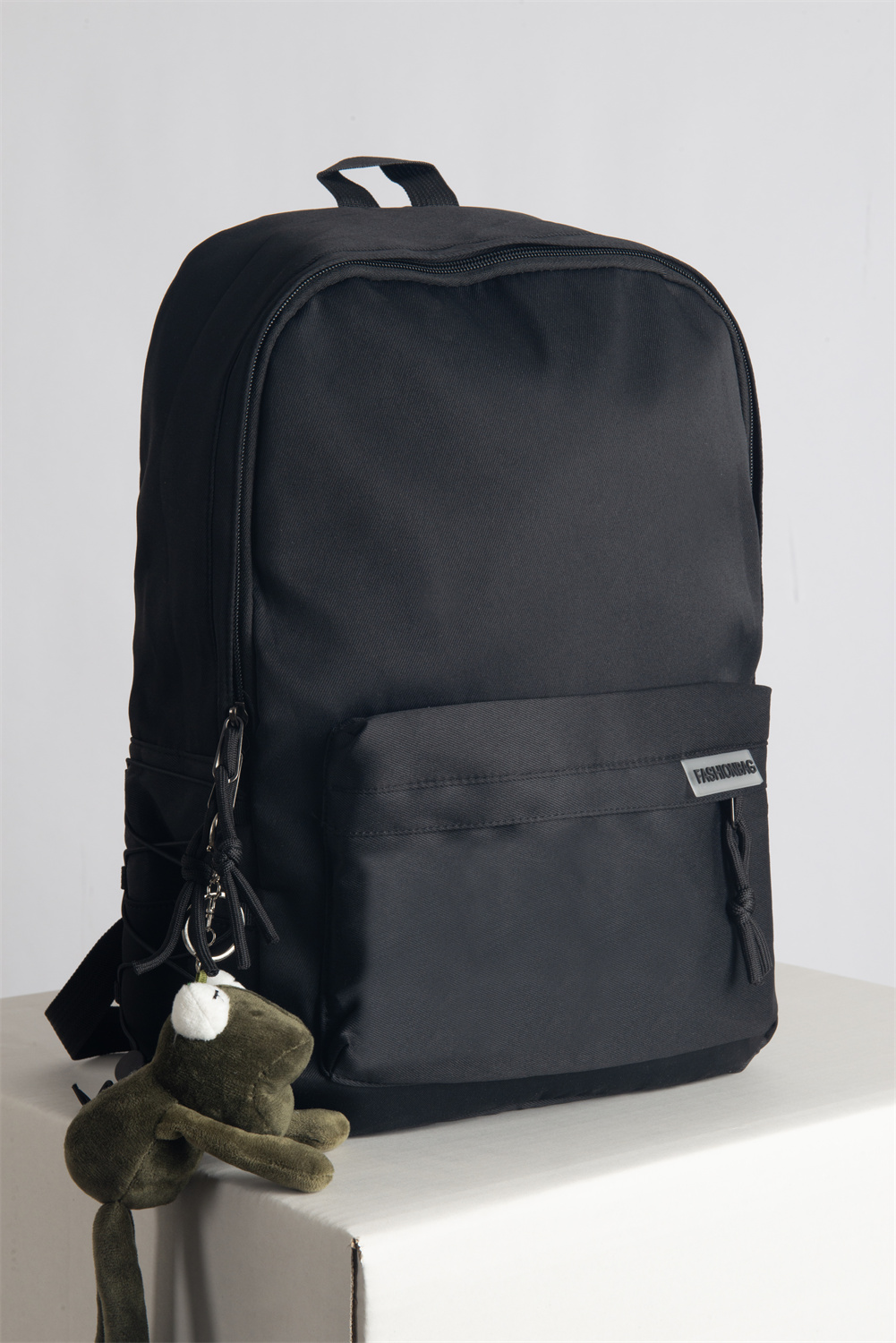 Minimalist Japanese backpack with anti-theft pocket, tech compartments, and stylish frog charm accessory.
