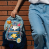 JINZU is a stylish medium-sized denim backpack adorned with playful, colorful pins—perfect for adding whimsy to your look. Lightweight and well-compartmentalized, it keeps your essentials organized whether you're heading to class or a casual party.