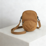 A mustard yellow mini crossbody bag named HATTO with a unique hat design and adjustable straps.