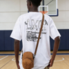 An American high schooler wearing the HATTO mustard yellow mini crossbody bag while standing on the school basketball court.