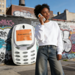 This lifestyle shot captures the Y2K aesthetic, featuring our signature phone-shaped crossbody held as a bold statement piece. Perfect for youth fashionistas looking to blend Japanese street style with urban utility.