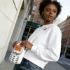 A young African-American lady showcasing her Japanese style crossbody phone bag on the streets of New York. The mini bag compliments her stylish streetwear.